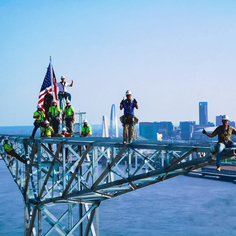 Workers standing on the top of a transmission tower