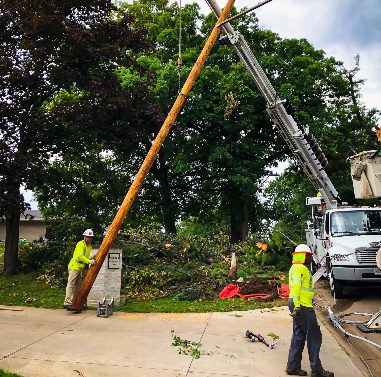 Restoration workers lifting a damaged power line pole