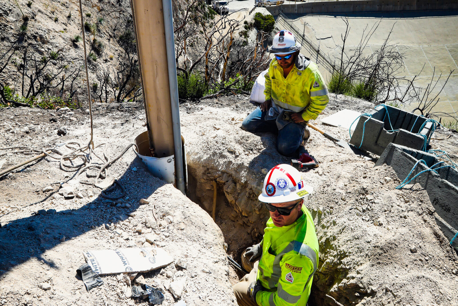 Two Sturgeon Electric workers looking at a small hole in the dirt