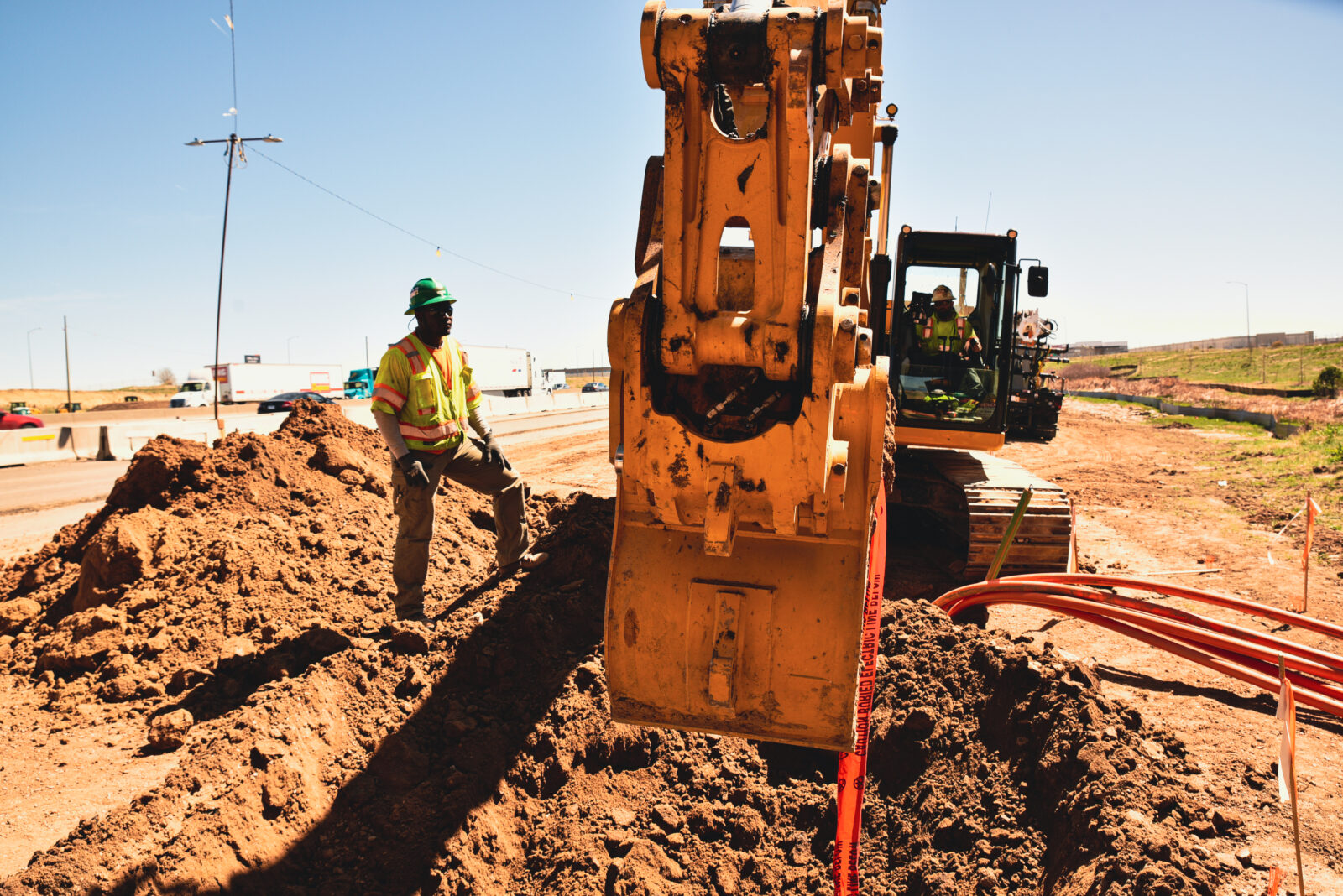 Construction worker observing an excavator digging into the dirt
