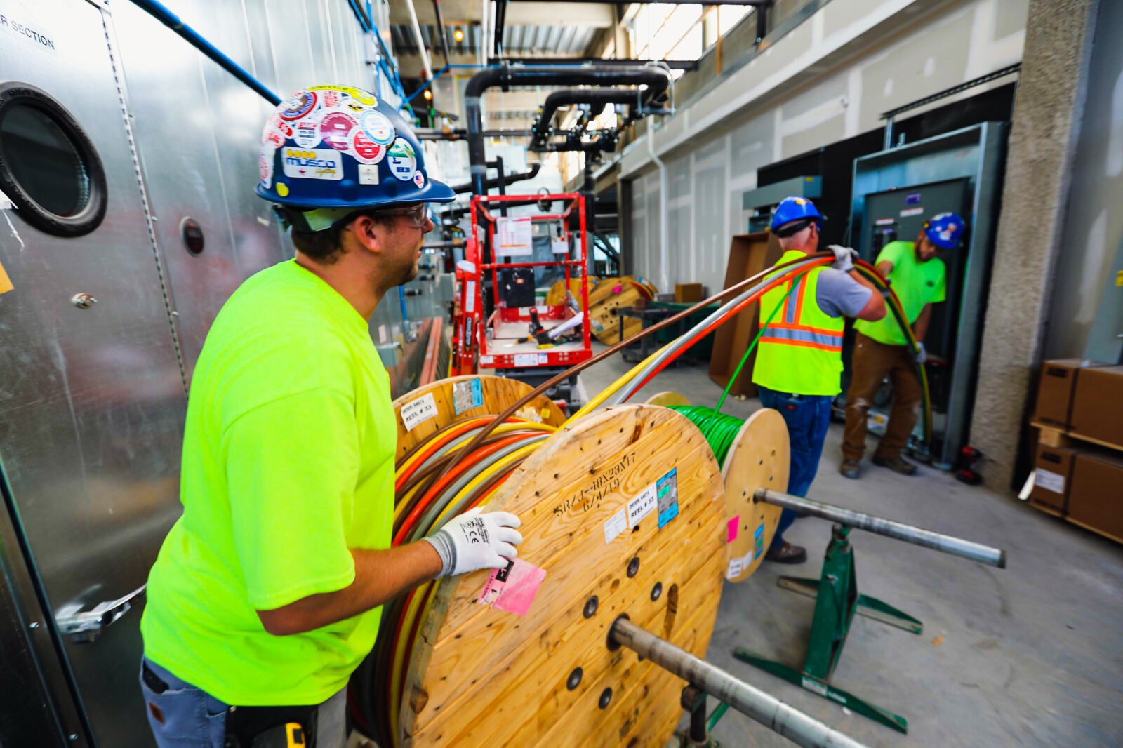ESB crews with safety gear rolling a wheel of wire into the construction zone