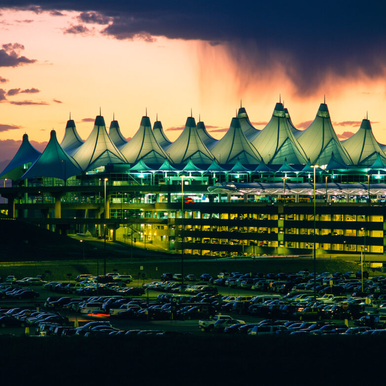 Denver International Airport's terminal and parking lot lit up at dusk