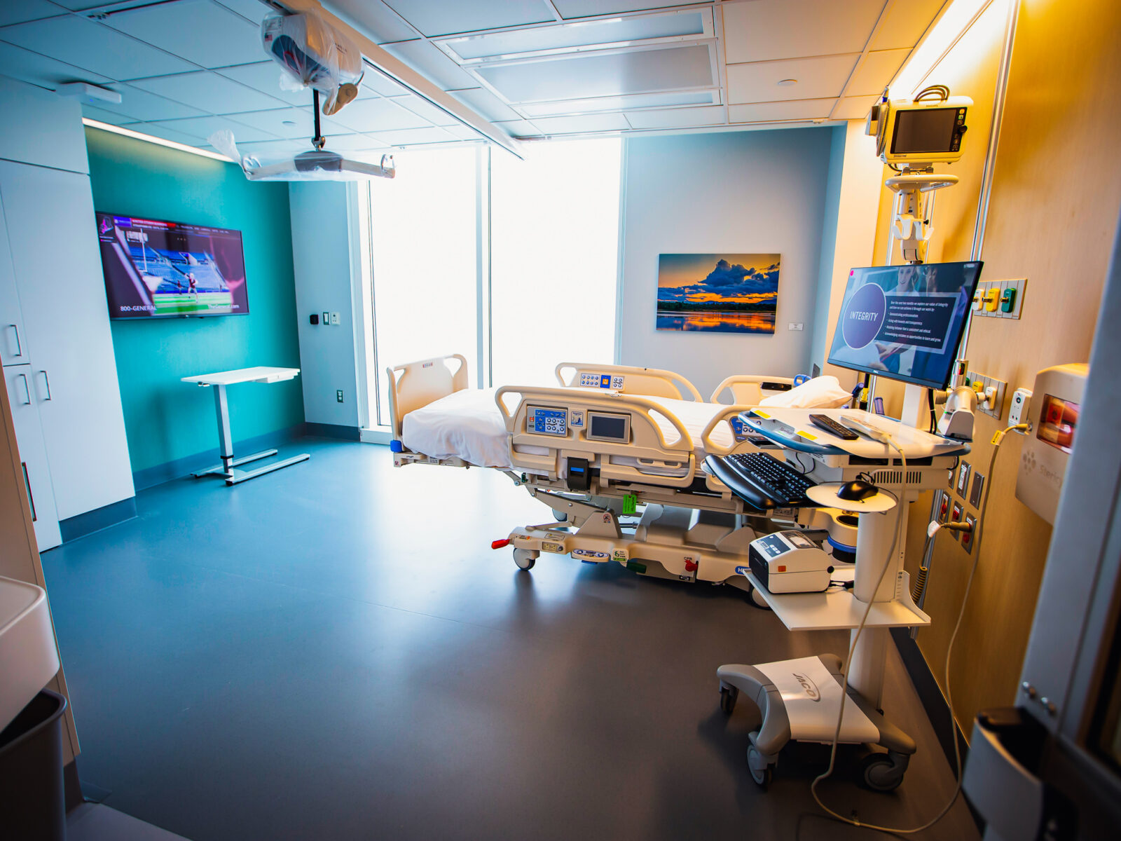 Hospital bed in a patient room of a hospital with light shining through the window