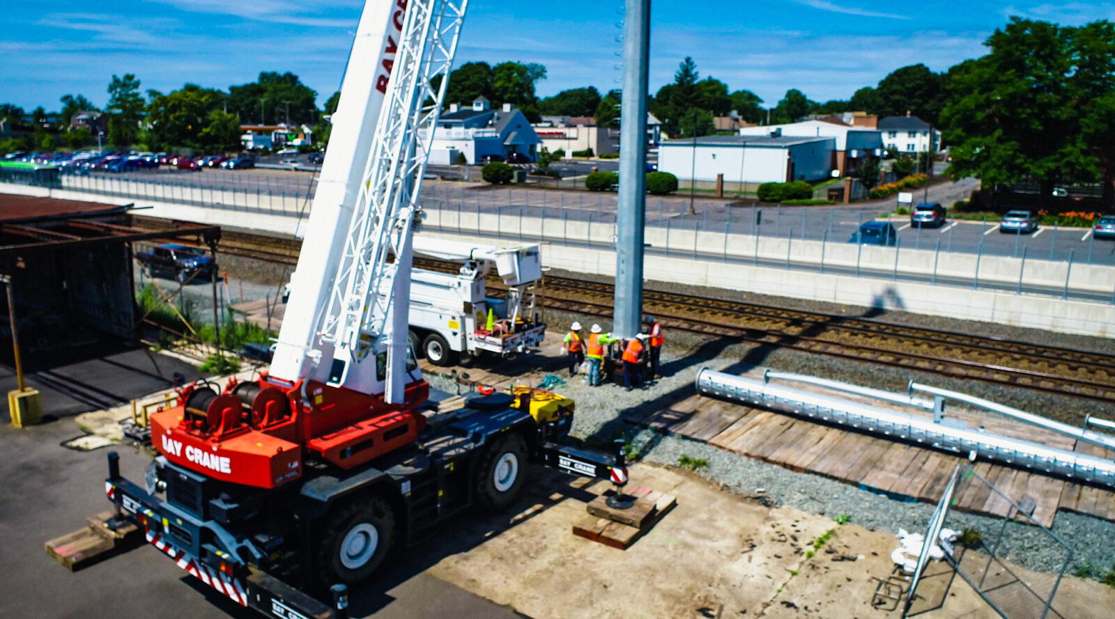 Construction workers with a white crane beside a railway
