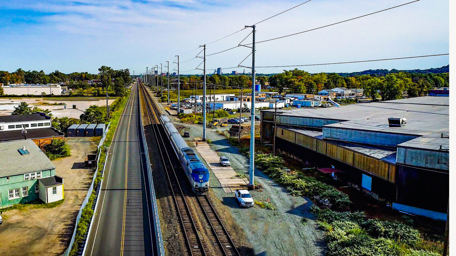 Railway train beside multiple buildings and a road