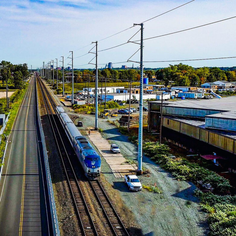 Railway train beside multiple buildings and a road