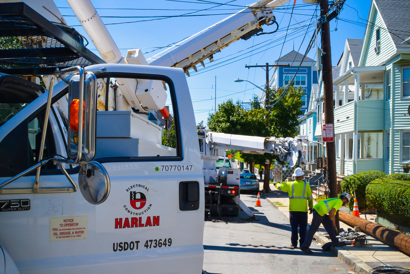 Close-up view of Harlan Electric logo on the door of a truck with workers in the distance