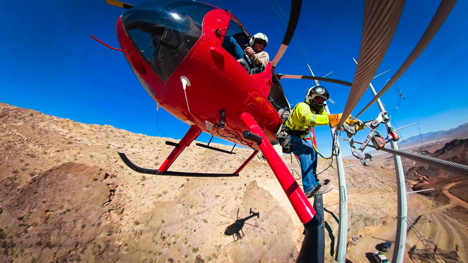 Two workers on a helicopter to reach and work on a power line