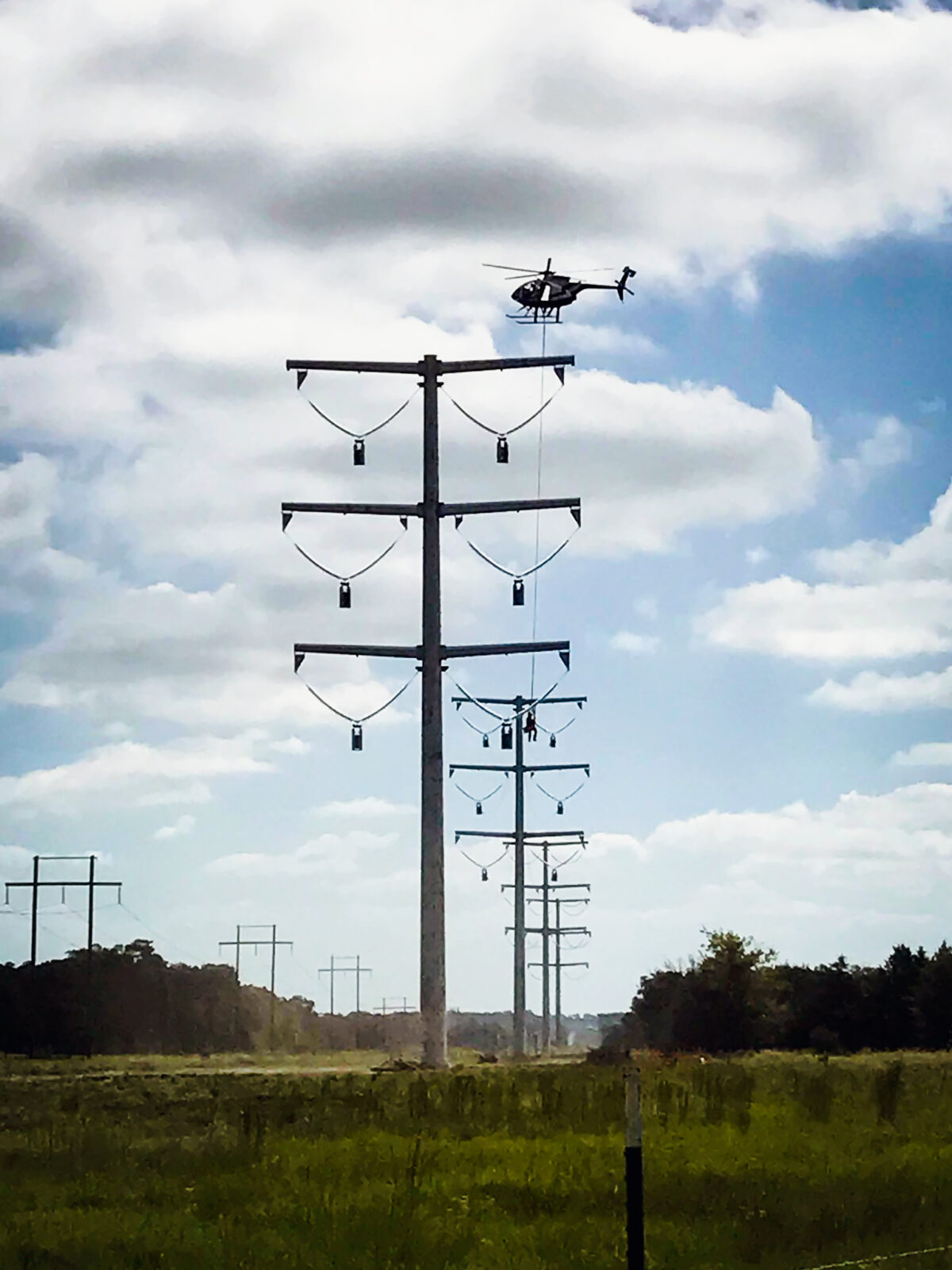 L.E. Myers employee is hoisted by a helicopter to access transmission lines