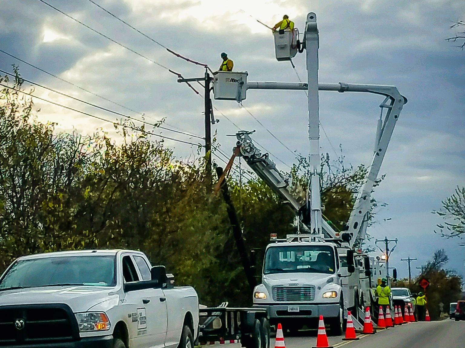 Restoration workers on bucket trucks beside a power line