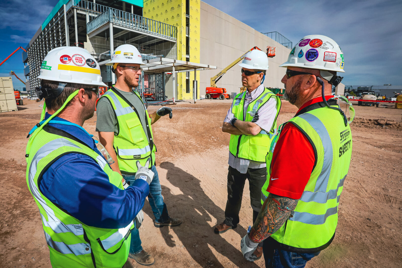 Four construction workers having a discussion in front of a construction site