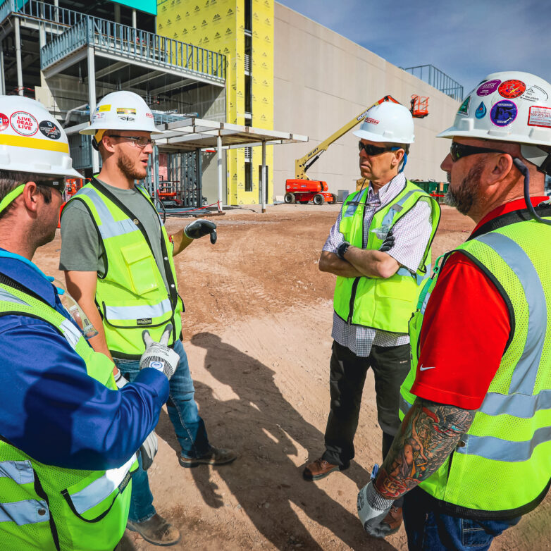 Four construction workers having a discussion in front of a construction site
