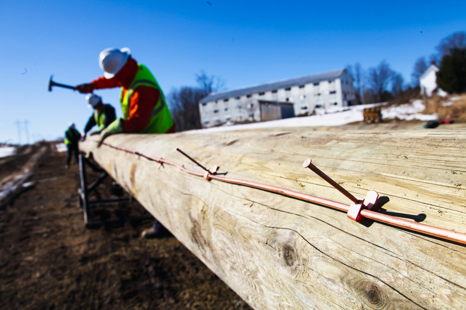 Two construction workers hammering nails on to a wooden pole