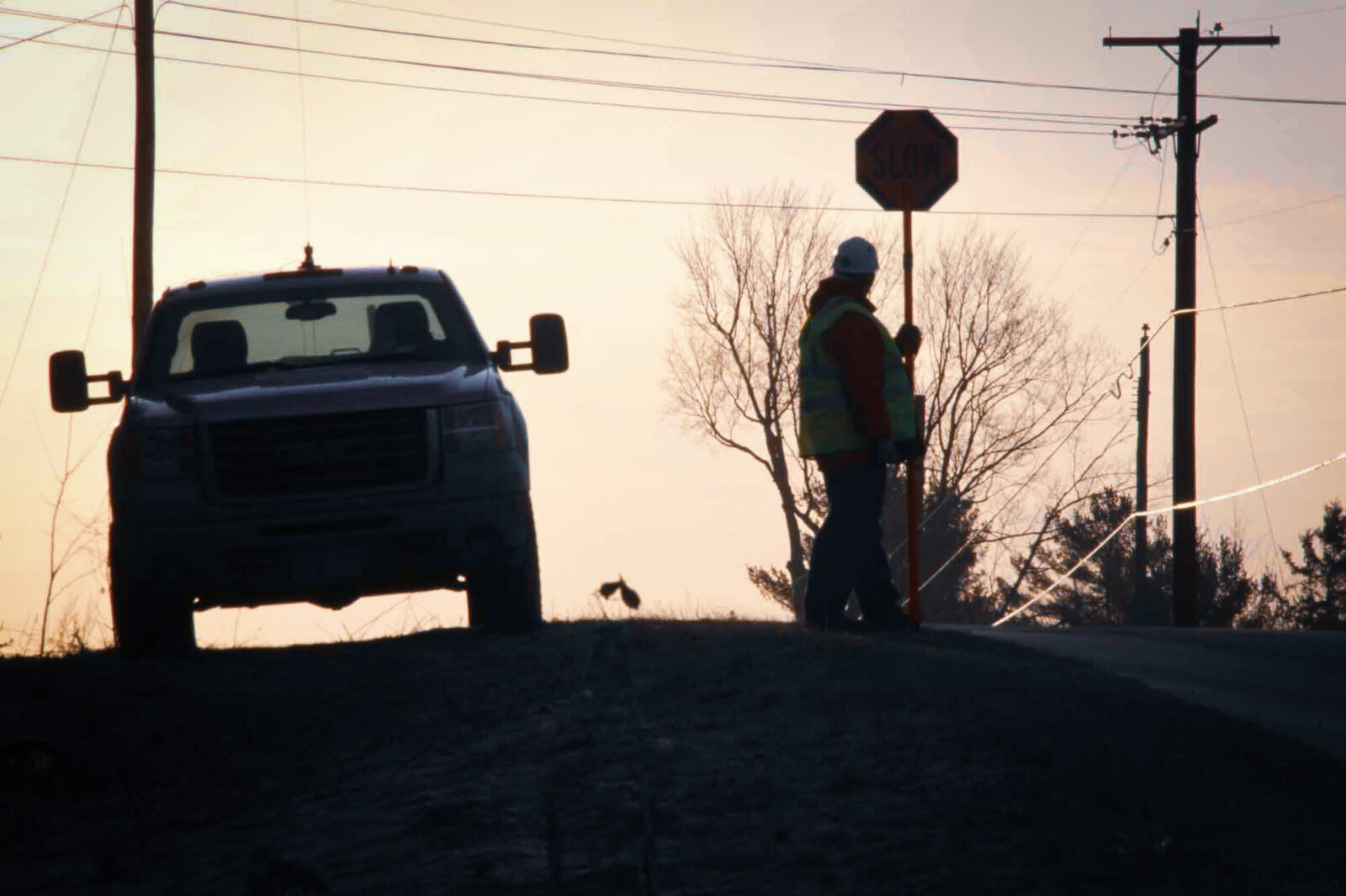 Construction worker holding a stop sign beside a road