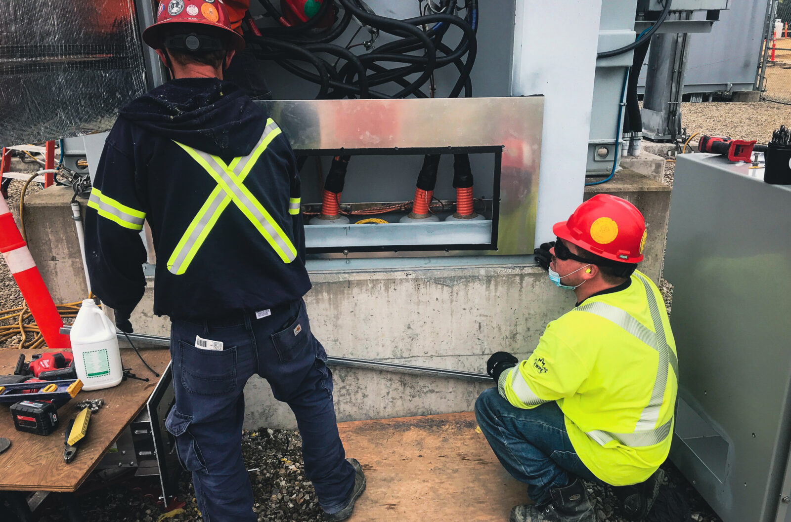 Two workers observing cables at a substation