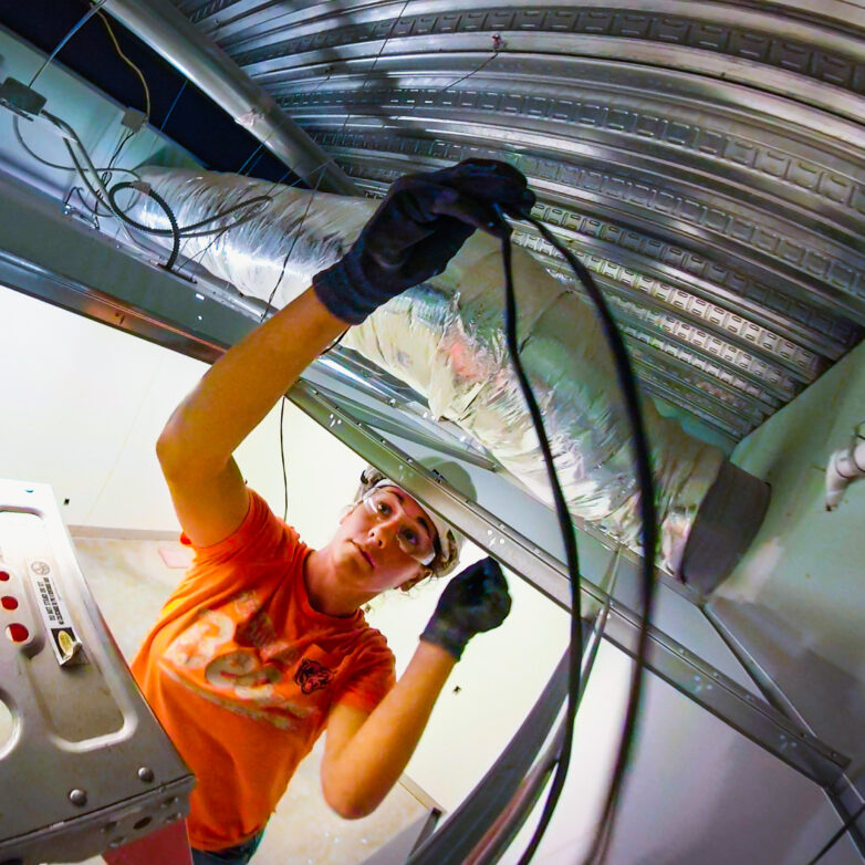 Huen worker on a ladder adjusting ceiling cables