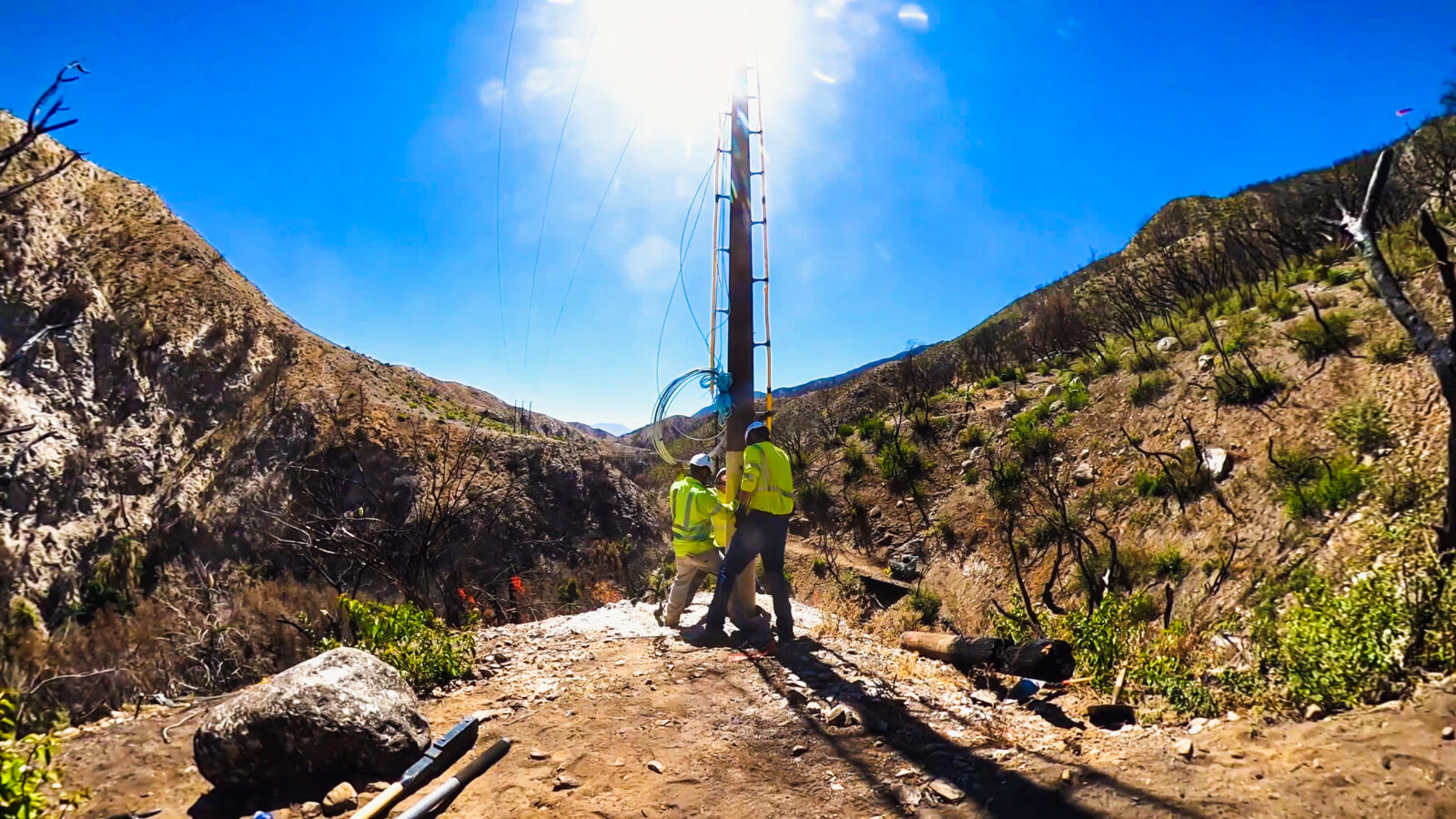 A few lineworkers setting a power line pole.