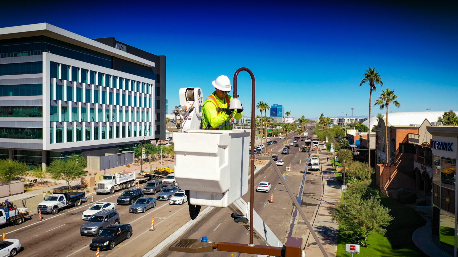 An electrical worker stands in a bucket truck while working on a streetlight