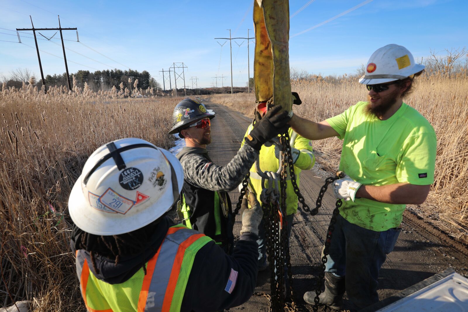 Four lineworkers holding chains.