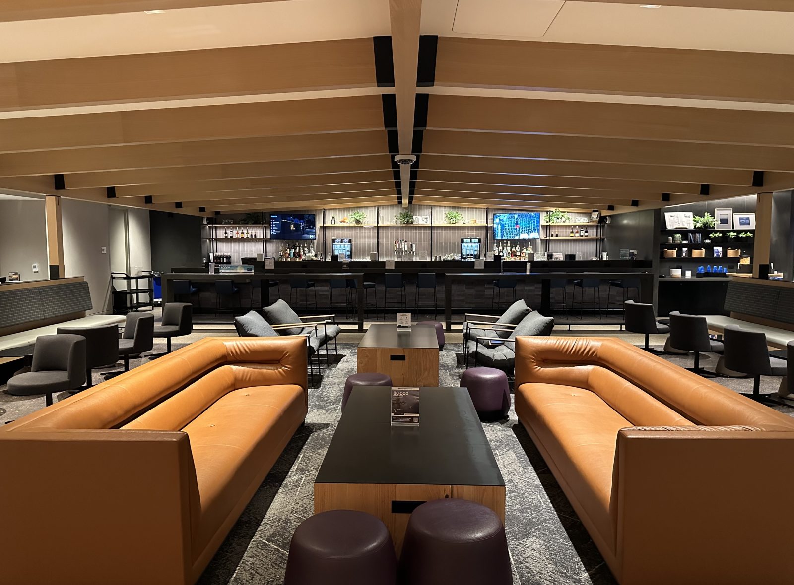 An empty room with brown couches and blue chairs and tables
