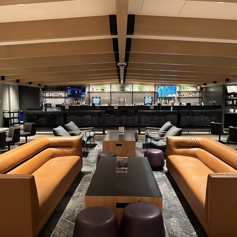 An empty room with brown couches and blue chairs and tables