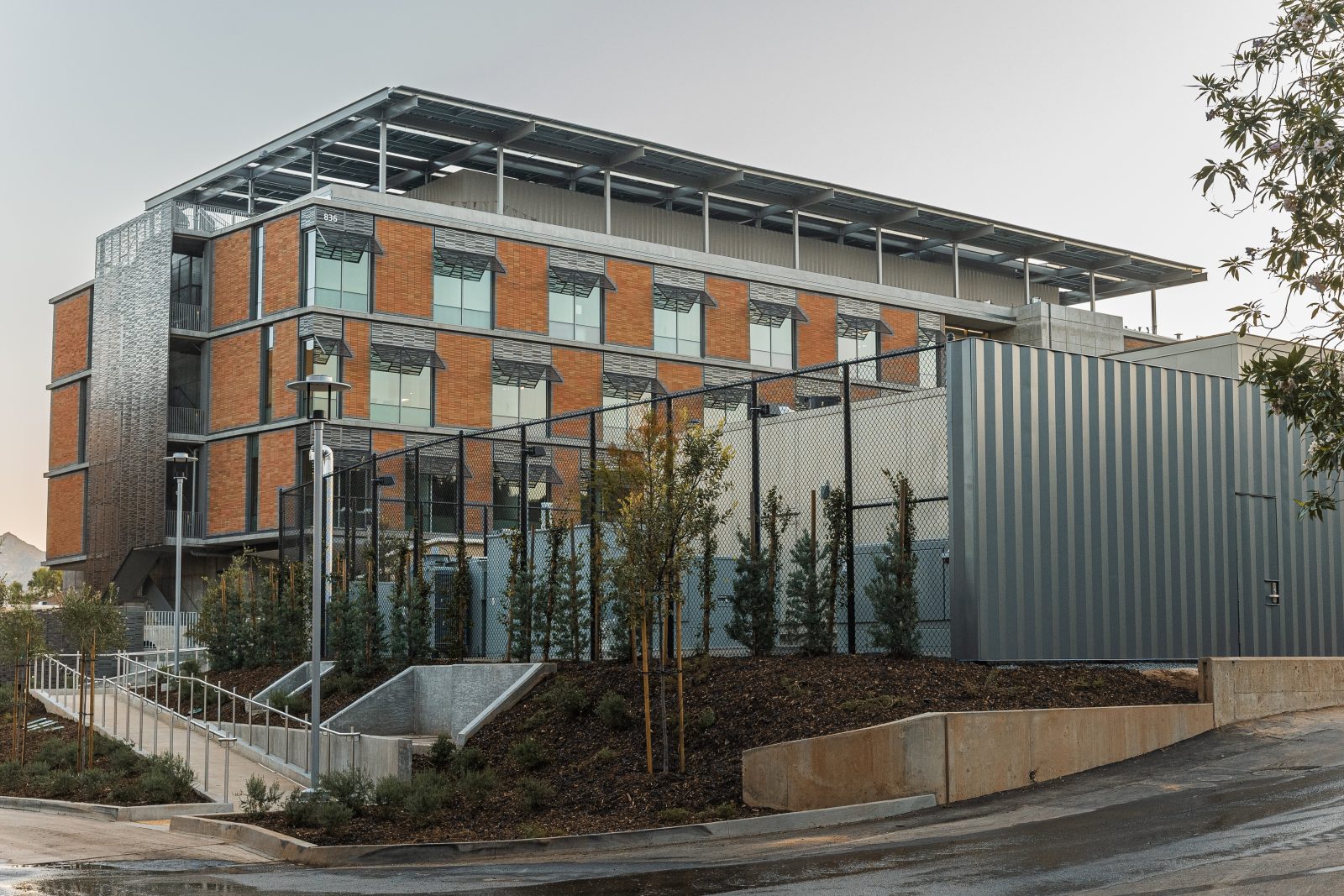 a large building with lots of windows, with a fenced area in front