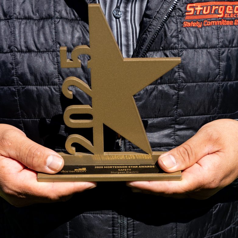 A man holds an star shaped award with 2025 on it.